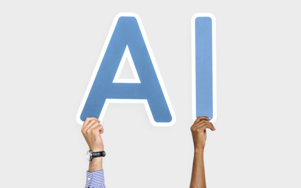 Hands holding up blue letters forming the abbreviation AI
